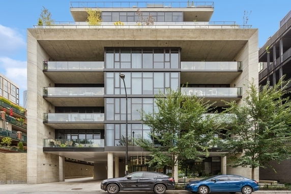 Front view of a multi-story residential building with balconies and glass facade.