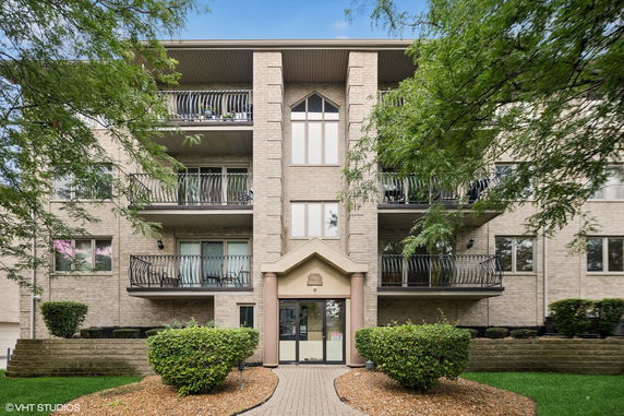 Front view of a multi-story residential building with balconies and entrance.