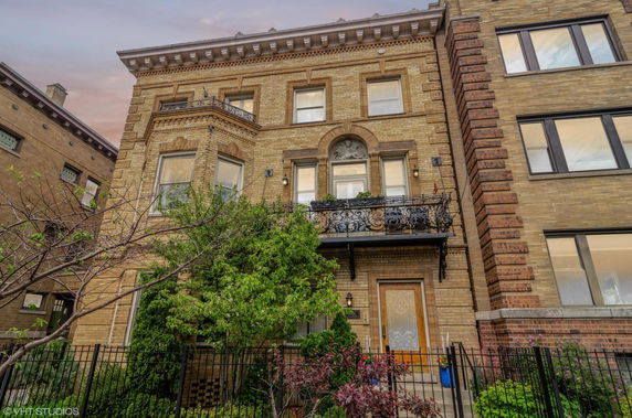 Front view of a brick multi-story building with decorative balcony.