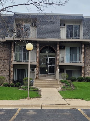 Front view of a multi-story residential building with balconies and a central entrance.