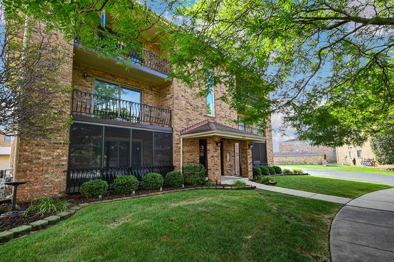 Front view of a multi-story brick building with balconies and a small entrance porch.