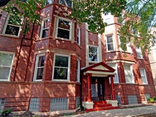 Front view of a multi-story brick building with bay windows and a covered entrance.