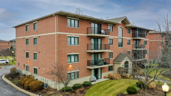 Front view of a four-story brick apartment building with balconies.