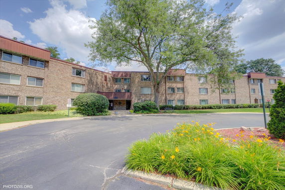 Front view of a multi-story brick building with large windows.