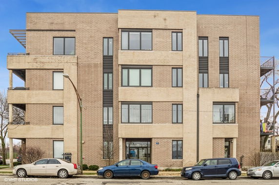 Front view of a multi-story building with large windows and brick facade.