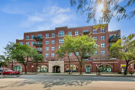 Front view of a multi-story brick building with balconies and arched windows.