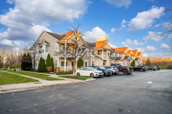 Front view of a multi-story residential building with a parking lot.