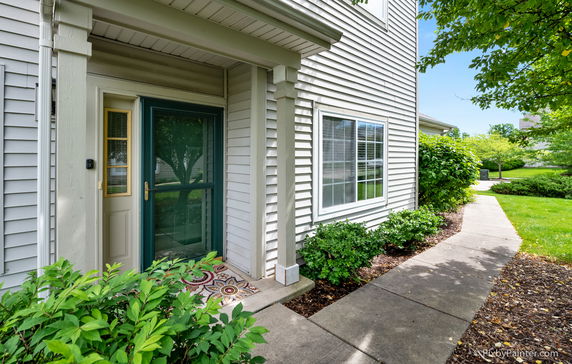 Front view of a house with white siding and a green entrance door.