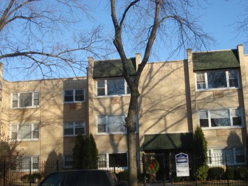 Front view of a three-story apartment building with green roof awnings.