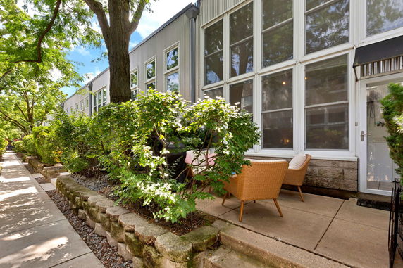 Front view of a modern building with large windows and a small outdoor seating area.