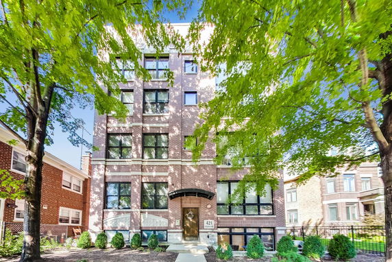 Front view of a multi-story brick building with large windows.
