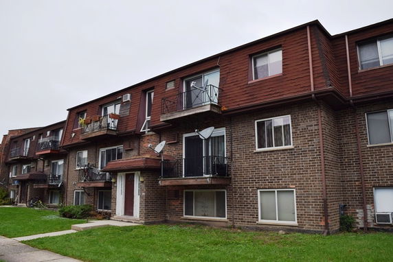 Front view of a multi-story apartment building with brick exterior and balconies.
