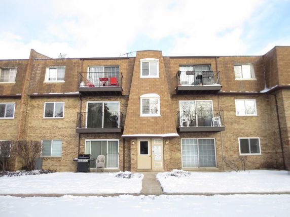 Front view of a three-story brick apartment building with balconies.