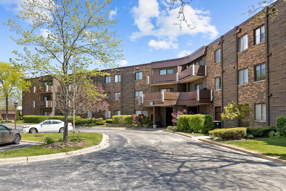 Front view of a three-story apartment building with brick exterior and balconies.