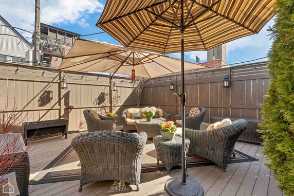 Rooftop patio with wicker furniture and umbrellas.