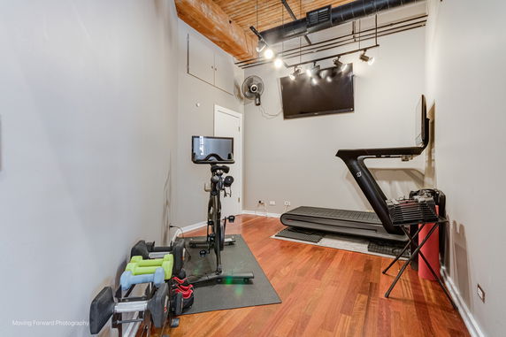 Indoor gym area with exercise bike, treadmill, and weights.