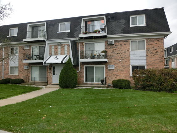 Front view of a three-story apartment building with balconies and a central entrance.