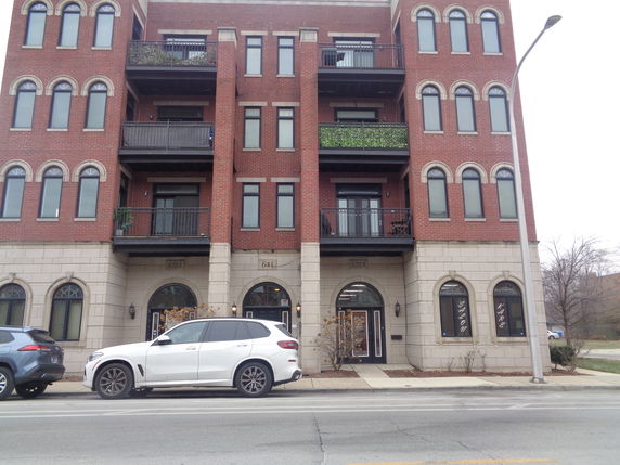 Front view of a multi-story brick building with balconies and arched windows.