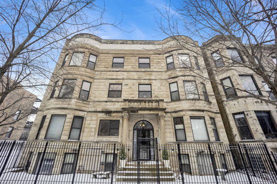 Front view of a multi-story stone building with arched entrance and multiple windows.