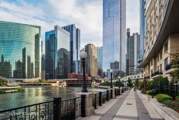 View of cityscape with tall buildings along a riverwalk.