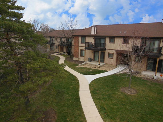 Front view of a two-story residential building with balconies and a walkway.