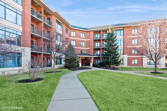 Front view of a multi-story brick building with balconies and an entrance.