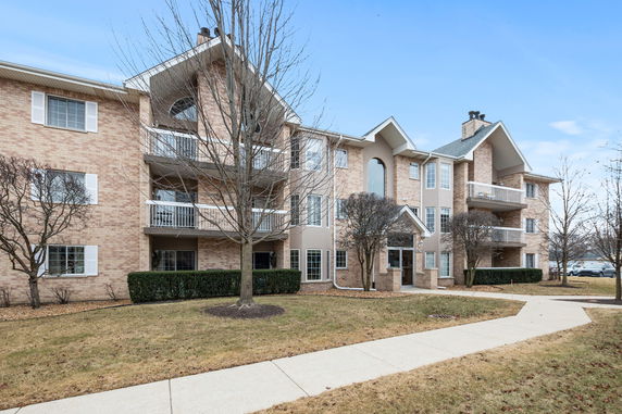 Front view of a multi-story brick apartment building with balconies.