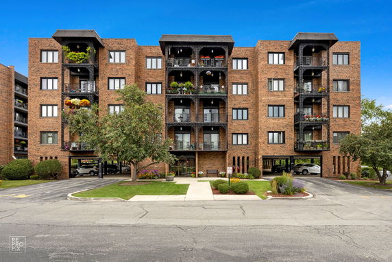 Front view of a multi-story brick apartment building with balconies and a central entrance.