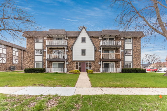Front view of a multi-story brick apartment building with balconies.