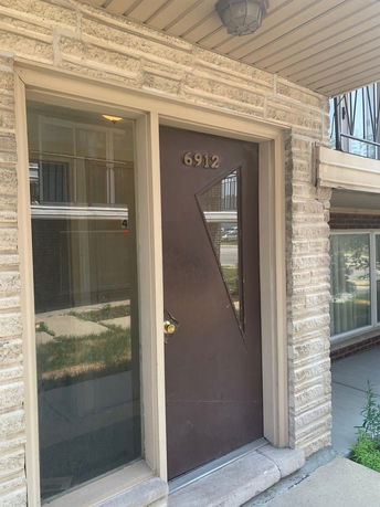Front view of a building entry with a brown door and address number 6912.