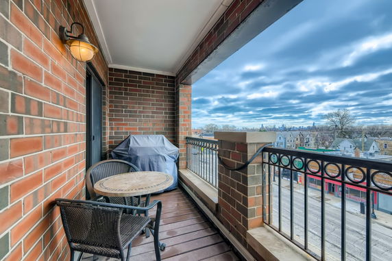 Balcony with a round table and two chairs, overlooking a cityscape.