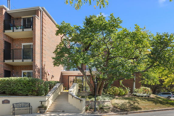 Front view of a brick multi-story residential building with balconies.
