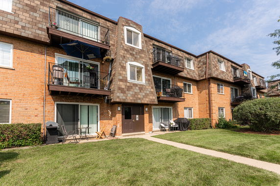 Front view of a three-story apartment building with balconies and brick exterior.