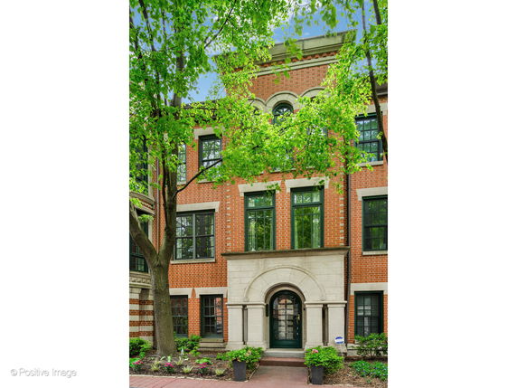 Front view of a three-story brick townhouse with decorative stone entrance.