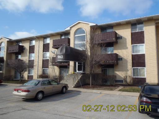 Front view of a multi-story apartment building with covered entrance.