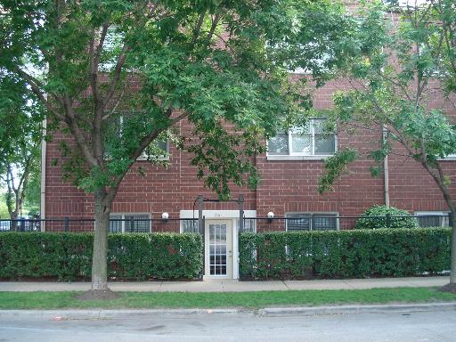Front view of a brick apartment building with a central entrance and windows on the upper floor.