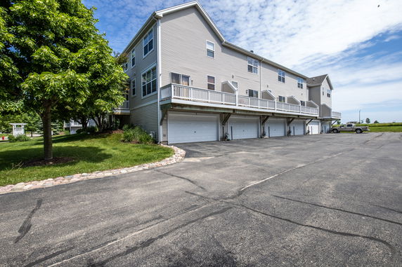 Outdoor parking area in front of a multi-story building with garages.