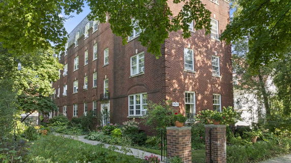Front view of a brick multi-story residential building with multiple windows.