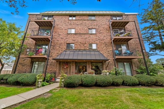 Front view of a four-story brick apartment building with balconies.