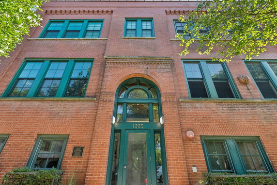 Front view of a multi-story brick building with green-framed windows.