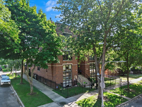Front view of a multi-story brick building with surrounding trees.