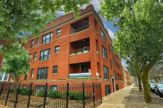 Front view of a multi-story red brick building with balconies.