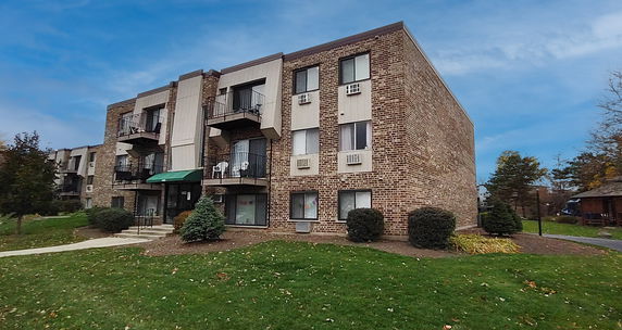 Front view of a multi-story brick apartment building with balconies.