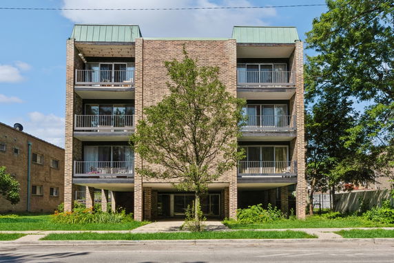 Front view of a three-story apartment building with balconies and a brick exterior.