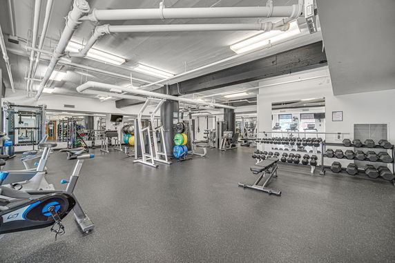 Indoor gym with exercise equipment and weights.
