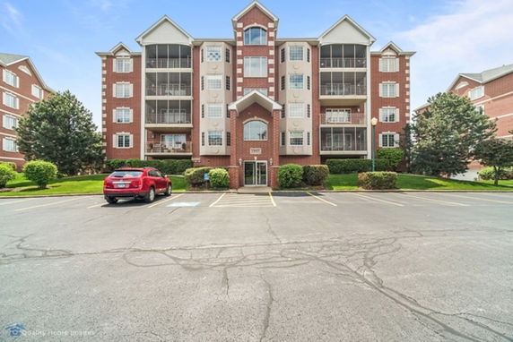 Front view of a multi-story residential building with balconies and brick facade.