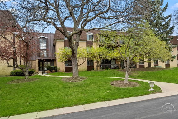 Front view of a two-story apartment building with a brown roof and large windows.