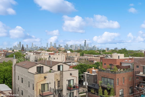 Panoramic view showing residential buildings with a city skyline in the background under a cloudy sky.