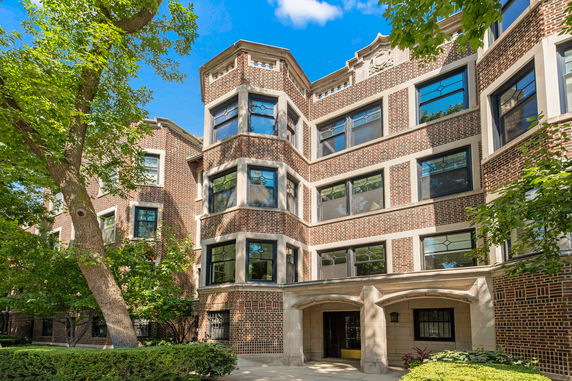Front view of a multi-story brick apartment building with large windows.