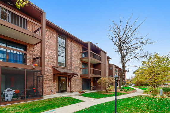 Front view of a multi-story brick apartment building with balconies.